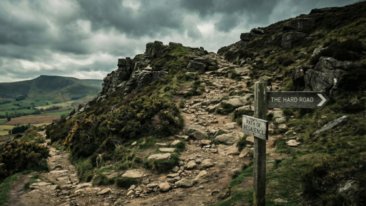 Rocky mountain path with sign to ‘The Hard Road’, symbolising tougher tax journey for high earners after UK Budget 2025.